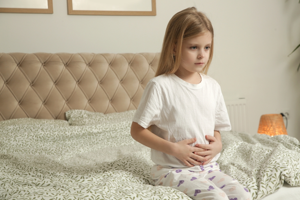 little,girl,sitting,on,bed,in,the,bedroom,with,stomach